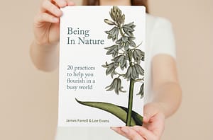 woman holding book called 'being in nature'