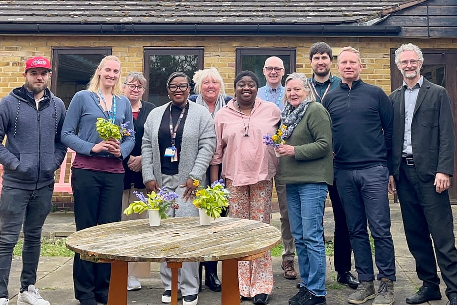 Men and women with flowers outside by wooden table